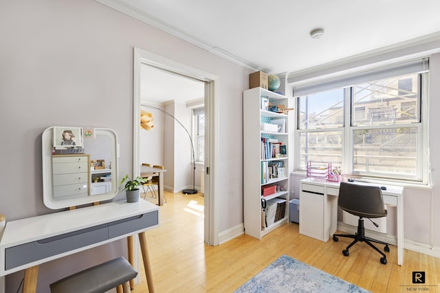 office space with baseboards, light wood-style floors, and ornamental molding