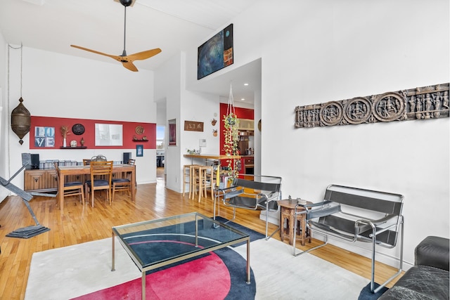 living area with high vaulted ceiling, a ceiling fan, and wood finished floors