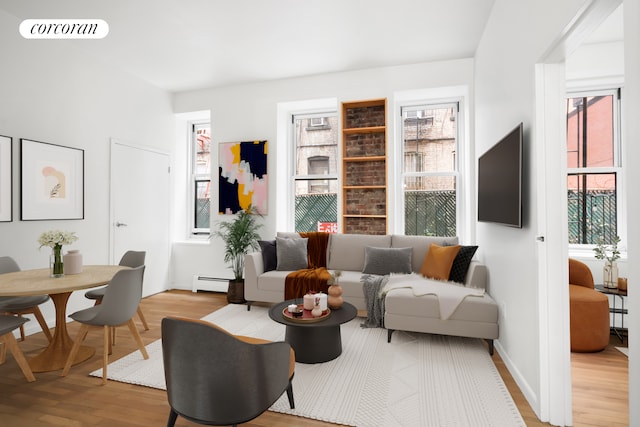 living area featuring baseboard heating, baseboards, light wood-type flooring, and visible vents