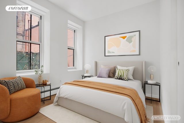 bedroom featuring baseboard heating and wood finished floors