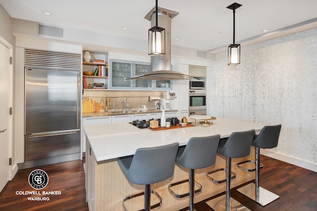 kitchen with light countertops, dark wood-style floors, built in appliances, and a sink