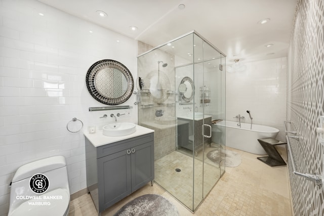 bathroom featuring vanity, recessed lighting, a stall shower, a freestanding bath, and tile walls