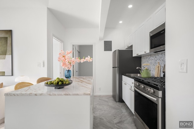 kitchen featuring electric panel, a sink, stainless steel appliances, white cabinetry, and tasteful backsplash