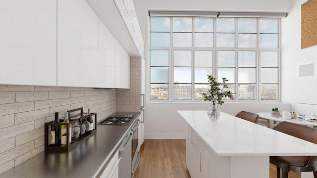 27-28 Thomson Ave Unit S415, New York City, NY 11101 - kitchen with white cabinetry, light wood-type flooring, plenty of natural light, and a center island