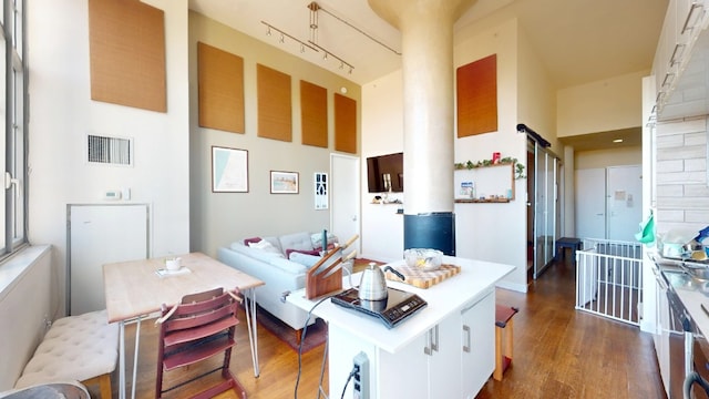 kitchen featuring visible vents, white cabinetry, rail lighting, a towering ceiling, and dark wood-style flooring