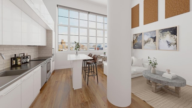 27-28 Thomson Ave Unit S415, New York City, NY 11101 - kitchen with a kitchen breakfast bar, modern cabinets, light wood-type flooring, white cabinets, and backsplash