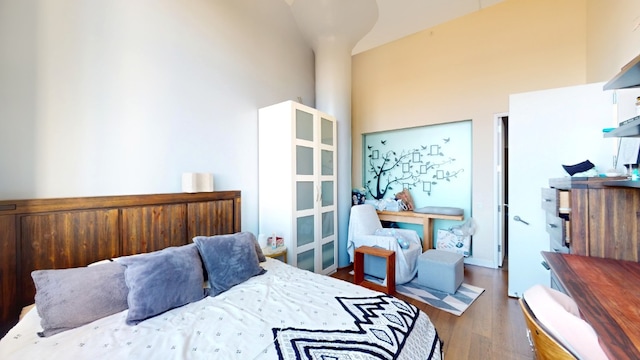 bedroom with wood finished floors and a towering ceiling