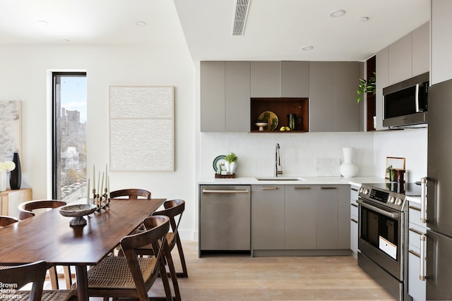 kitchen with a sink, gray cabinets, and stainless steel appliances