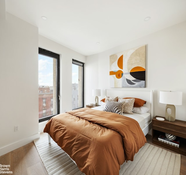 bedroom with baseboards, wood finished floors, and access to outside