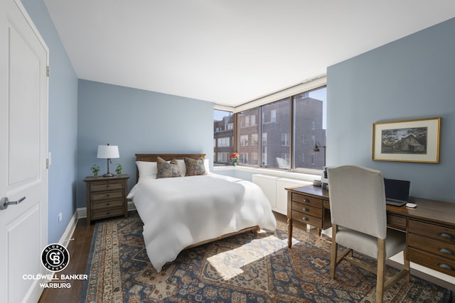 bedroom featuring wood finished floors, an office area, and baseboards