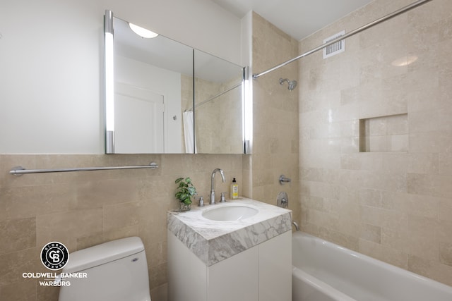 full bath with washtub / shower combination, tile walls, toilet, and vanity