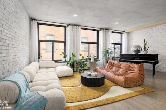 living area featuring wood finished floors and brick wall