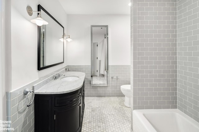 full bathroom featuring tile patterned flooring, tile walls, toilet, and wainscoting