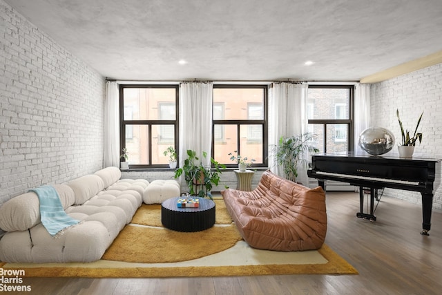 living room featuring a healthy amount of sunlight, brick wall, and wood finished floors