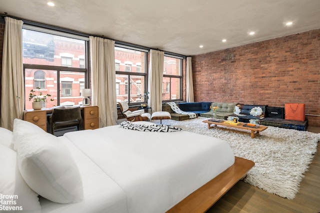 bedroom with recessed lighting, brick wall, and wood finished floors