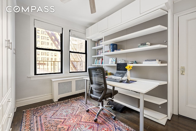 office space with dark wood-style floors, ceiling fan, radiator heating unit, and baseboards