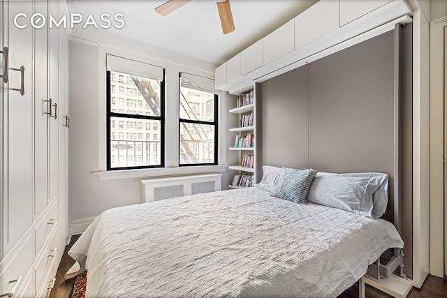 bedroom with a ceiling fan, radiator heating unit, and dark wood-type flooring