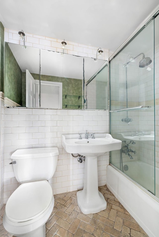 full bath featuring backsplash, enclosed tub / shower combo, toilet, and tile walls