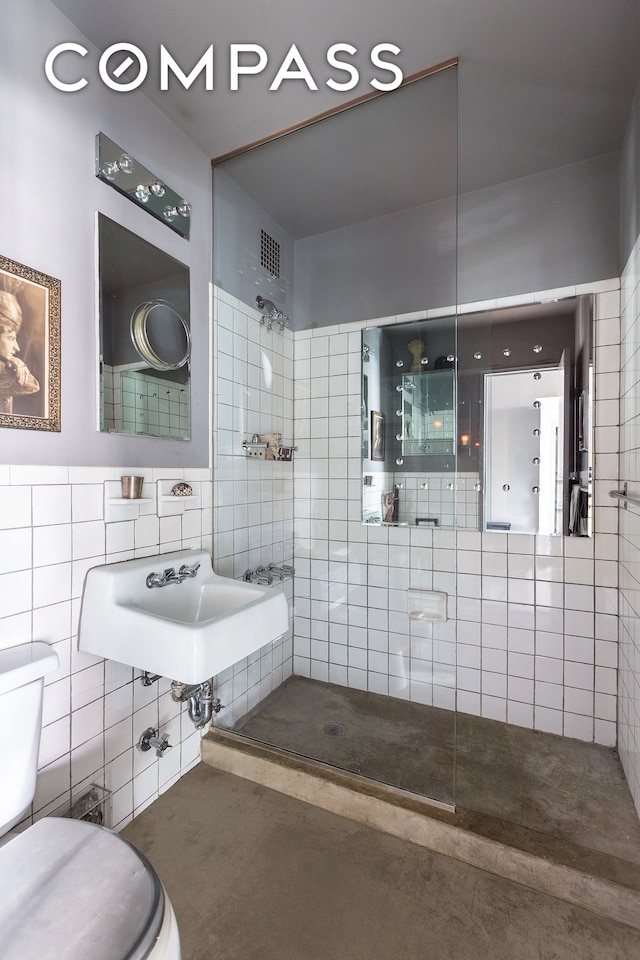 bathroom with visible vents, toilet, a sink, tile walls, and tiled shower