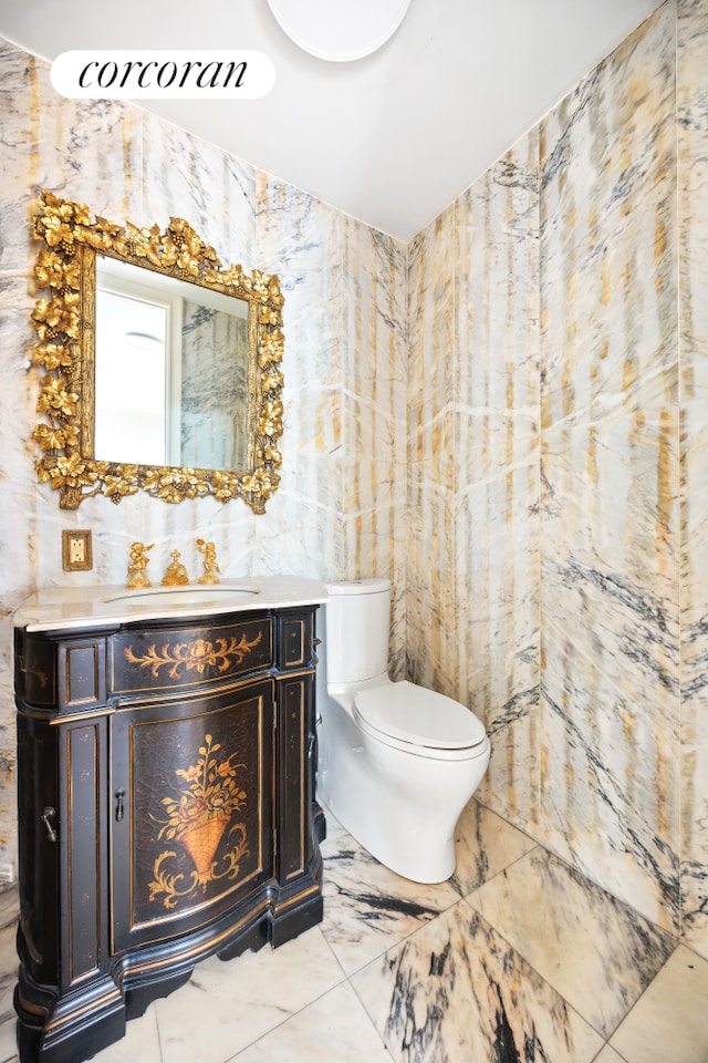 bathroom with vanity, tile walls, toilet, and marble finish floor