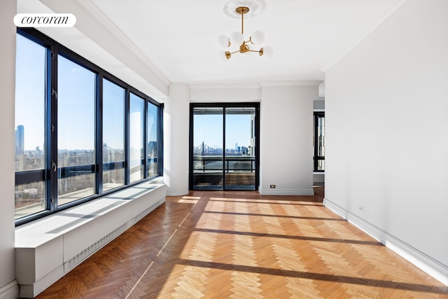 unfurnished room featuring a chandelier, a view of city, baseboards, visible vents, and ornamental molding