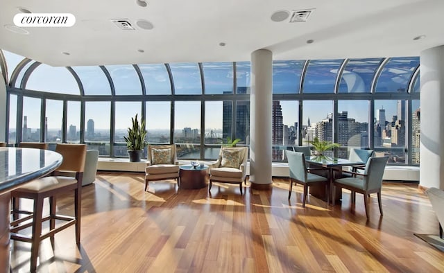 sunroom featuring a healthy amount of sunlight, a view of city, and visible vents