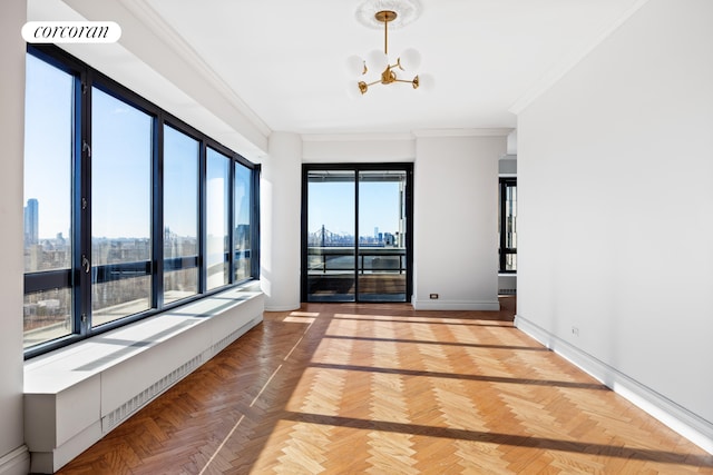 spare room featuring a view of city, a notable chandelier, baseboards, and ornamental molding