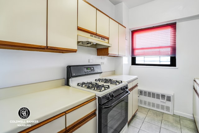 kitchen with range with gas stovetop, light tile patterned flooring, radiator heating unit, light countertops, and under cabinet range hood