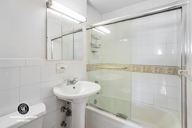 full bathroom featuring enclosed tub / shower combo, toilet, and tile walls