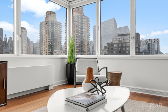 sitting room featuring a view of city, wood finished floors, and baseboards