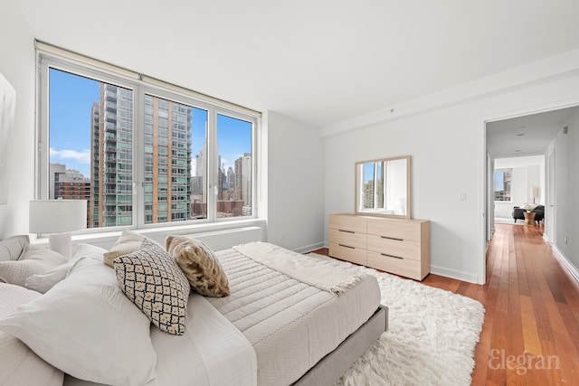 bedroom featuring a city view, baseboards, and wood-type flooring