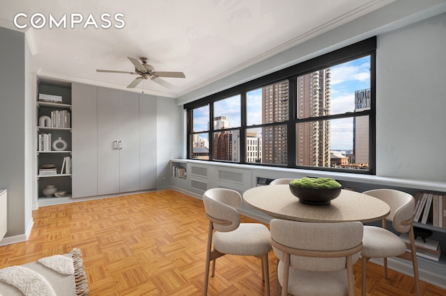 dining area featuring a city view, baseboards, a ceiling fan, and ornamental molding