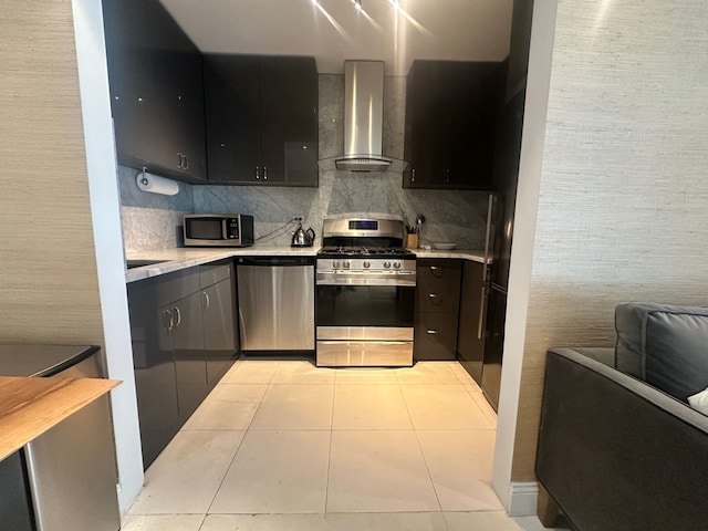 kitchen with light tile patterned floors, decorative backsplash, light countertops, appliances with stainless steel finishes, and wall chimney exhaust hood