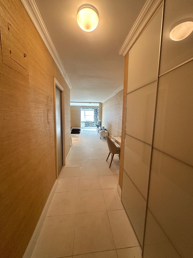 corridor with baseboards, light tile patterned flooring, and crown molding