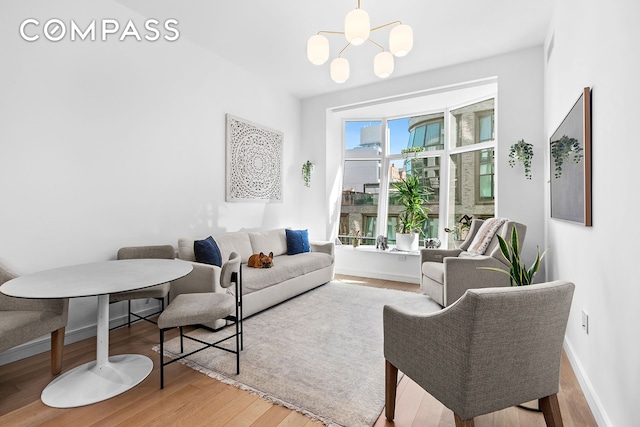 living area with a chandelier, baseboards, and wood finished floors