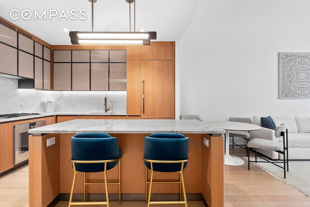 515 W 18th St Unit 403, New York City, NY 10011 - kitchen featuring oven, a sink, a breakfast bar area, and light stone counters