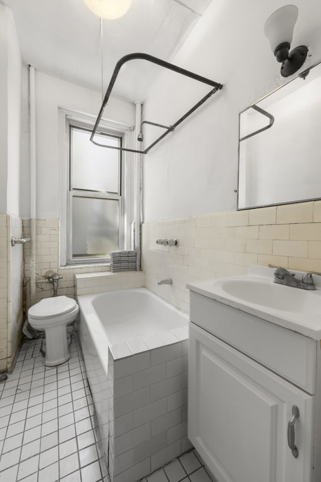 bathroom with tile patterned floors, toilet, tiled shower / bath combo, tile walls, and vanity