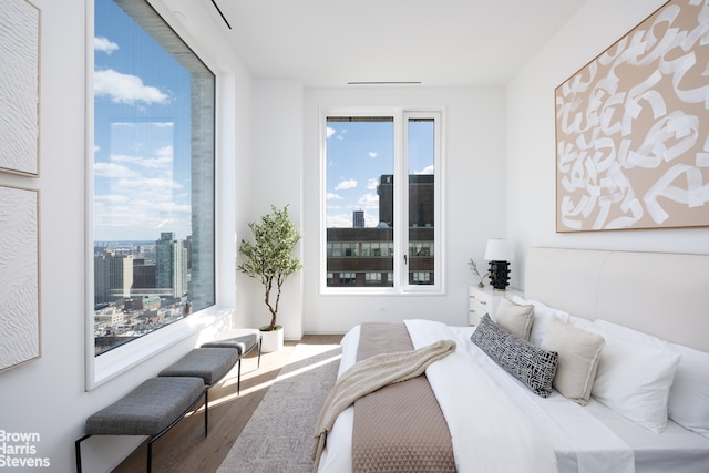 bedroom with a view of city and wood finished floors