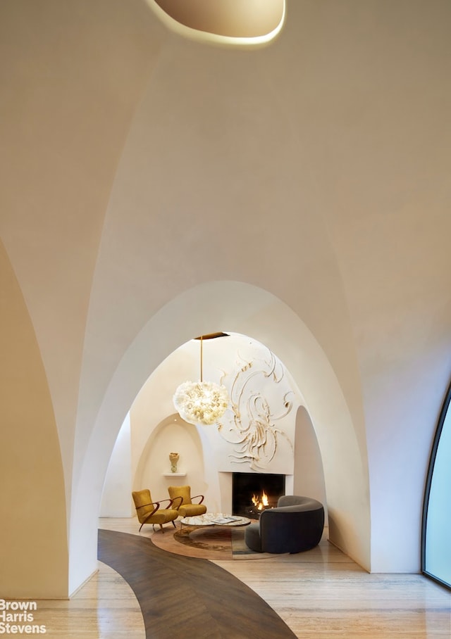 room details featuring arched walkways, a lit fireplace, an inviting chandelier, and wood finished floors