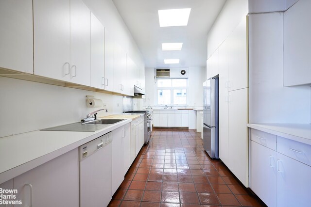 920 5th Ave Unit 10B, New York City, NY 10021 - kitchen with appliances with stainless steel finishes, a sink, under cabinet range hood, light countertops, and white cabinetry
