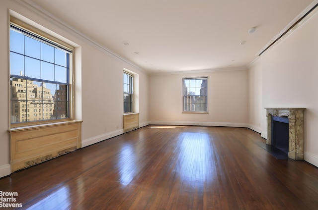 unfurnished living room with a fireplace, crown molding, baseboards, and wood finished floors