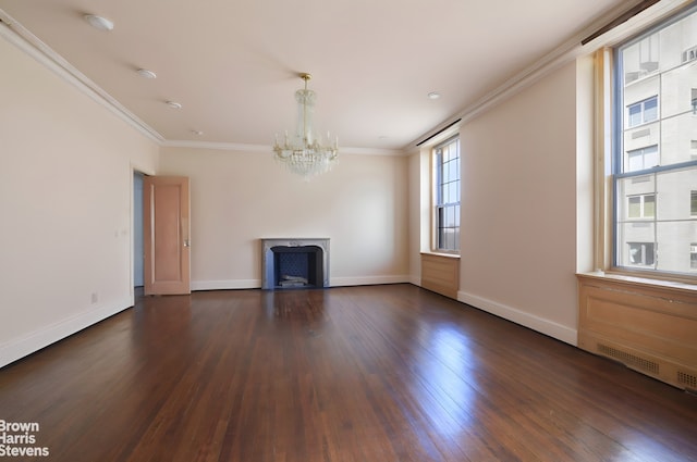 unfurnished living room with a notable chandelier, dark wood finished floors, a fireplace, crown molding, and baseboards