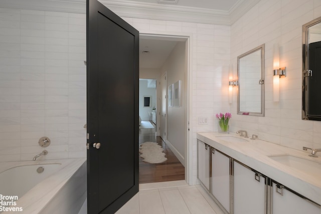 bathroom with a sink, tile walls, crown molding, tile patterned flooring, and a bath