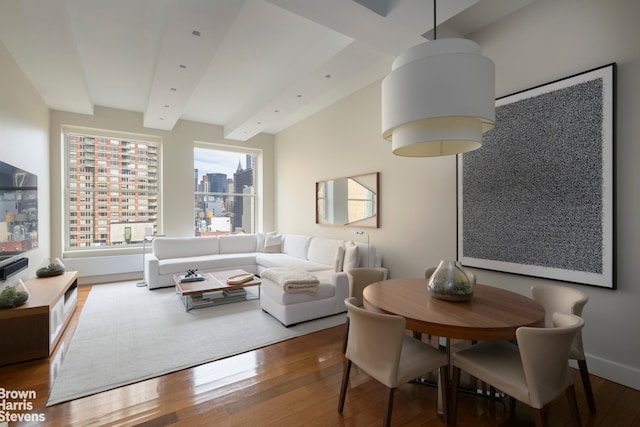 dining room with beamed ceiling, a view of city, baseboards, and hardwood / wood-style flooring