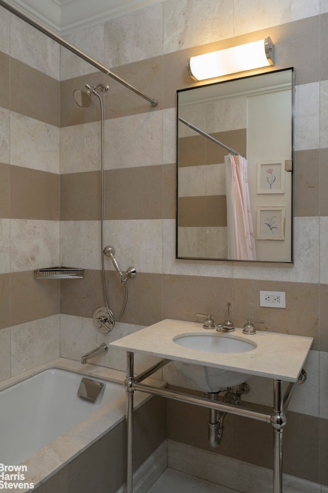 bathroom with decorative backsplash, tile walls, tiled shower / bath combo, and a sink