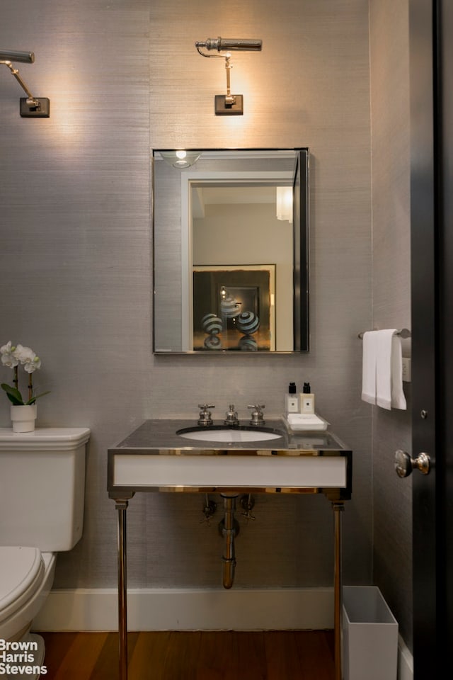 bathroom with toilet, wood finished floors, and a sink