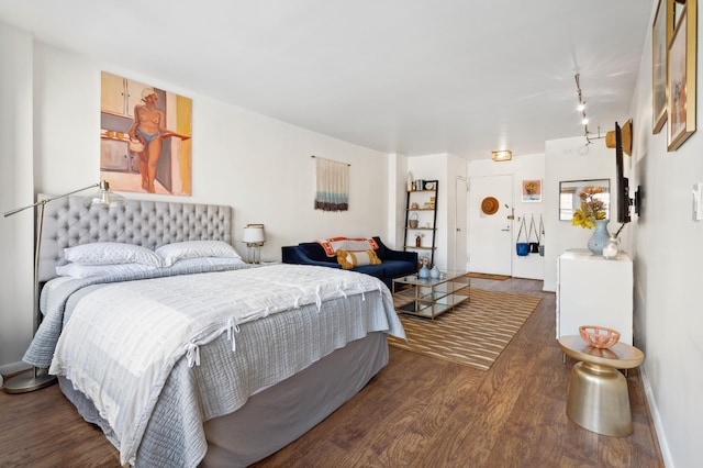 bedroom with baseboards, wood finished floors, and rail lighting