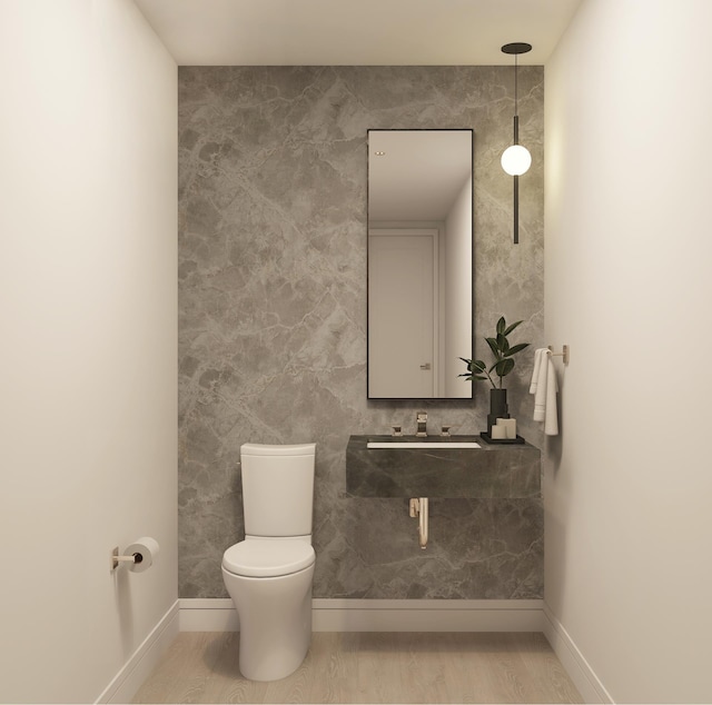 bathroom with a sink, baseboards, toilet, and wood finished floors