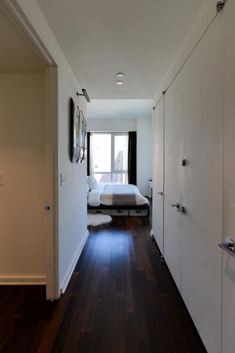 hallway with dark wood finished floors and baseboards