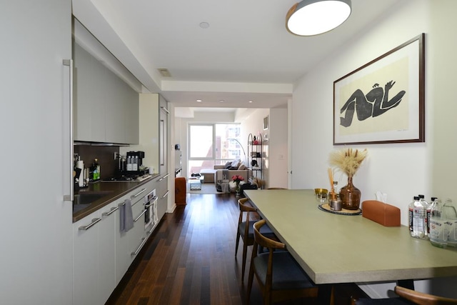 kitchen with white cabinets, a kitchen breakfast bar, modern cabinets, and dark wood-style flooring